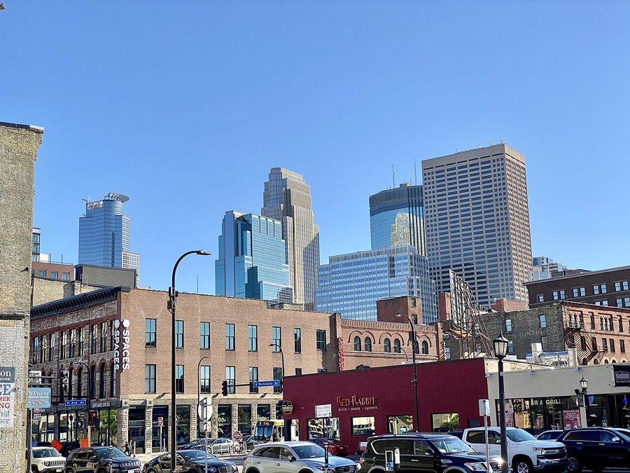 Downtown Minneapolis storefronts on Washington Avenue with the city skyline behind — the kind of local businesses Ali works with.